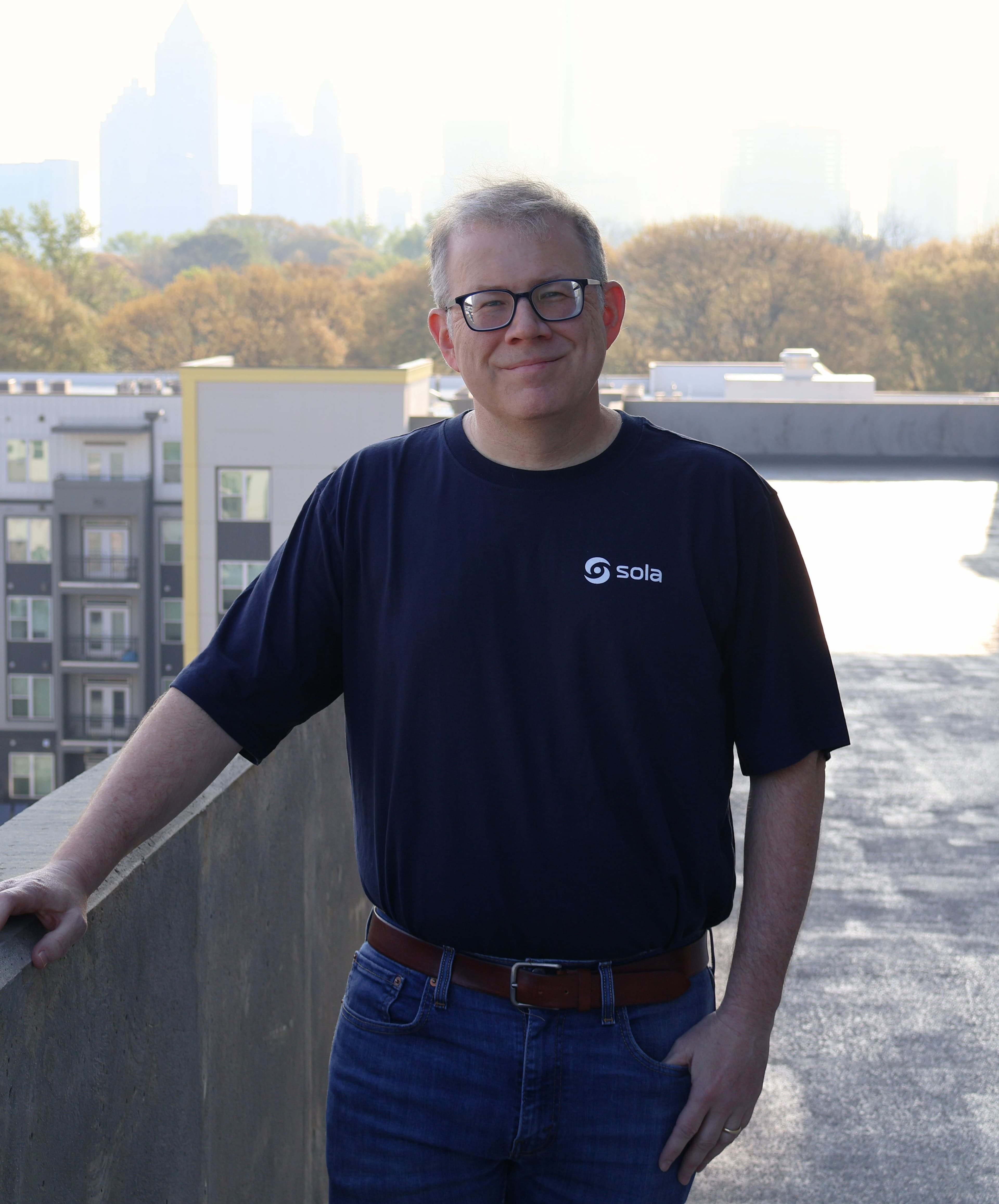 a man in a black tshirt and jeans standing outside